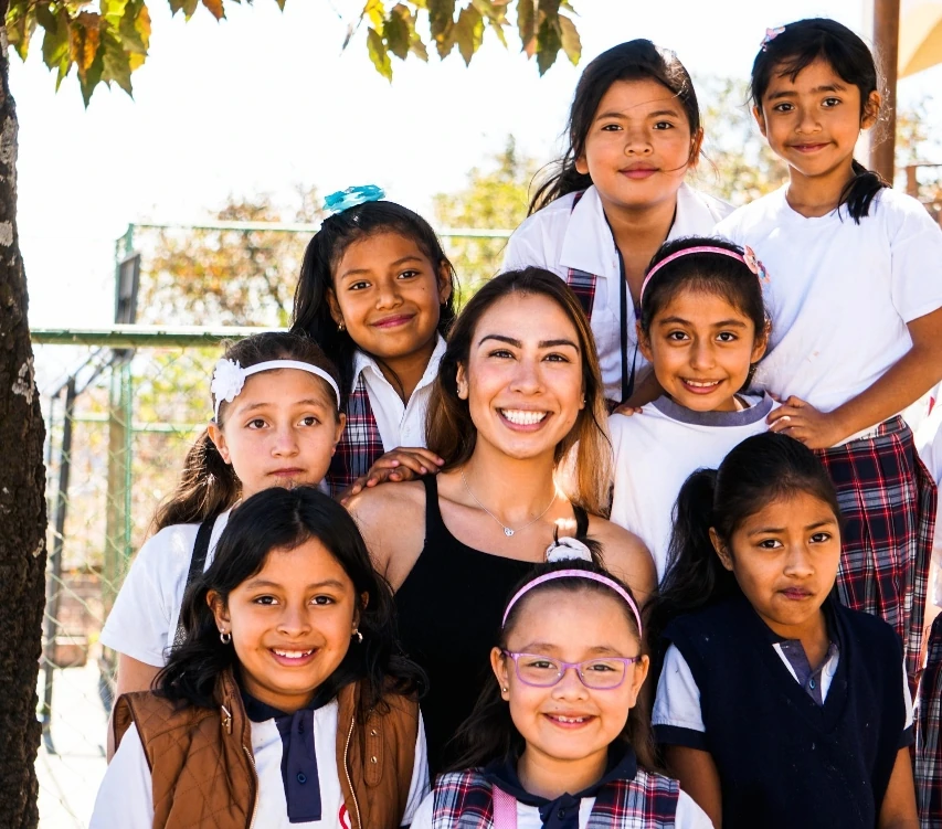 dental charity Guatemala A group of young girls in school uniforms posing with a woman in a black tank top, smiling and